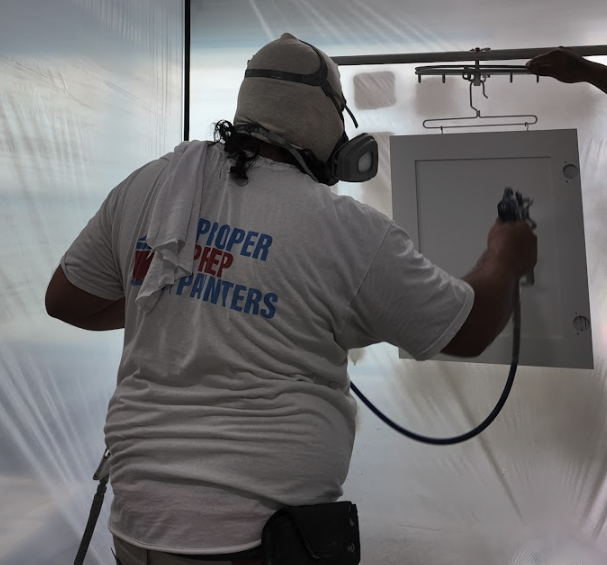 spraying a cabinet door in a plastic booth